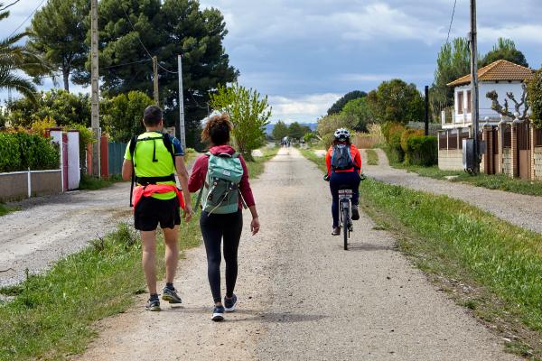 A couple is walking and a cyclist passes by